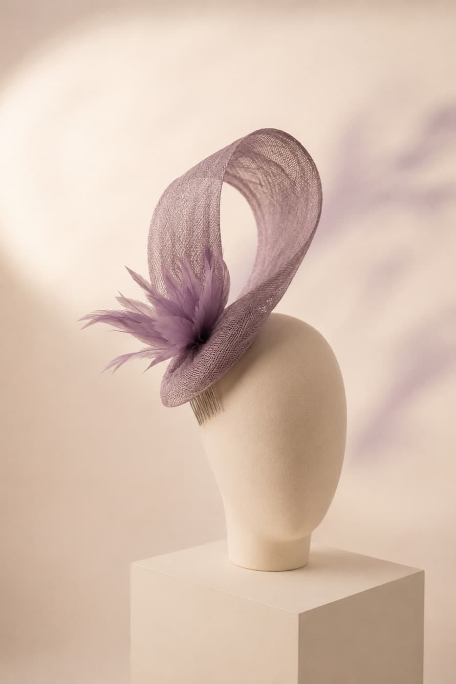 Looped sinamay fascinator angled on a featureless display block